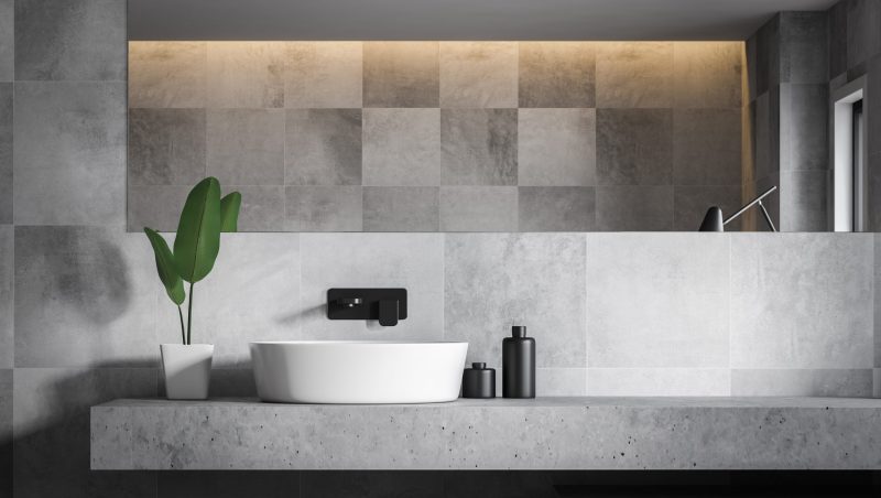Close up of stylish bathroom sink standing on stone shelf in bathroom with gray tile walls and large mirror. 3d rendering