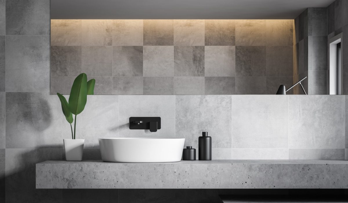 Close up of stylish bathroom sink standing on stone shelf in bathroom with gray tile walls and large mirror. 3d rendering